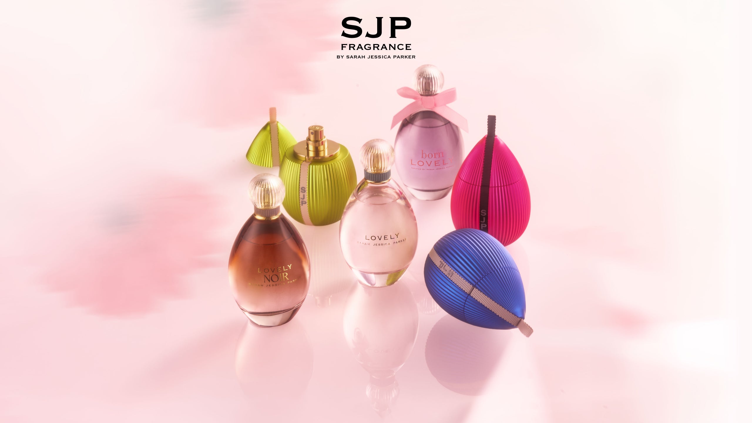 Collection of SJP Fragrances by Sarah Jessica Parker on a soft pink background.