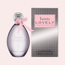 A bottle of Sarah Jessica Parker 'born LOVELY' Eau de parfum spray next to its packaging box, set against a solid pale pink background.