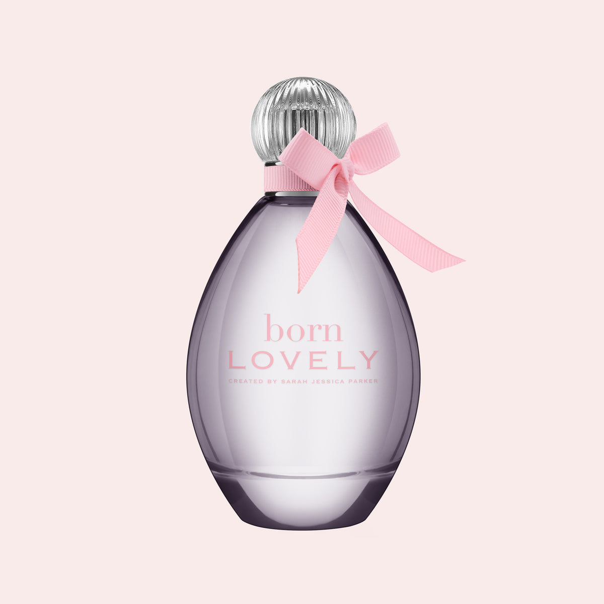 A bottle of Born Lovely fragrance by Sarah Jessica Parker, featuring a translucent lavender-purple teardrop-shaped bottle with a silver ribbed cap and a pink ribbon bow tied around the neck, set against a solid pale pink background.