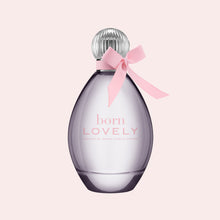 A bottle of Born Lovely fragrance by Sarah Jessica Parker, featuring a translucent lavender-purple teardrop-shaped bottle with a silver ribbed cap and a pink ribbon bow tied around the neck, set against a solid pale pink background.